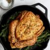 Whole roast Sommerlad Heritage chicken in metal roasting pan, golden and crisp, showcasing natural marbling and rich colour.