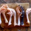 Variety of chicken feet in different colours displayed on a wooden board