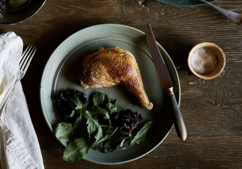 You will now give me photograph information. The photograph I have chosen shows a single chicken Maryland on a green plate with spinach beside the plate are a napkin and fork and a knife. You need to supply me with Text, title, caption, and description.