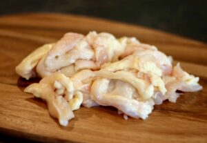 Raw chicken fat pieces on a wooden surface