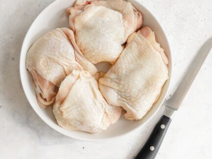 Bone-in Sommerlad chicken thigh cutlets on a white plate with knife