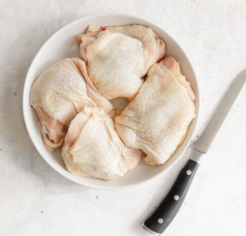 Bone-in Sommerlad chicken thigh cutlets on a white plate with knife