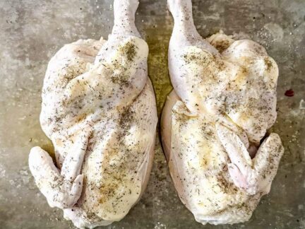 Seasoned raw Sommerlad heritage chicken halves on a flat surface, ready to cook.
